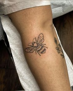 a small bee tattoo on the right arm and leg, it is black and white