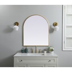 a bathroom vanity with an oval mirror above it and two lights on the wall next to it