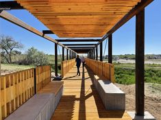 two people walking down a long wooden walkway