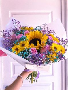 a person holding a bouquet of flowers in front of a door with purple and yellow colors