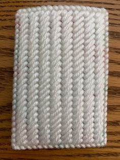 a piece of white knitted material sitting on top of a wooden table