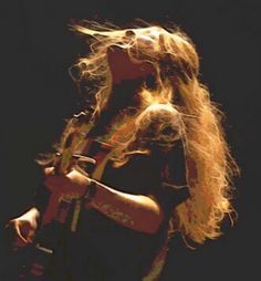 a woman with long blonde hair holding a guitar