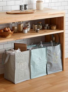 three bags sitting on top of a wooden shelf in front of a counter with spices