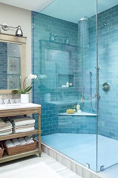 an image of a bathroom with blue tile on the walls and shower in the middle