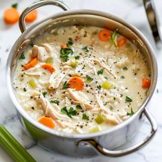 a pot filled with chicken and carrots on top of a marble counter next to green beans