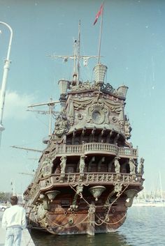 a man standing next to a large wooden ship