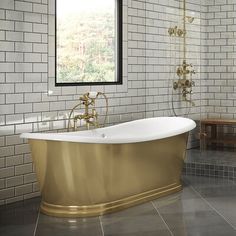 a bath tub sitting next to a window on top of a tiled floor in a bathroom