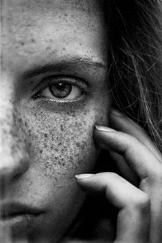 a black and white photo of a woman with freckles on her face