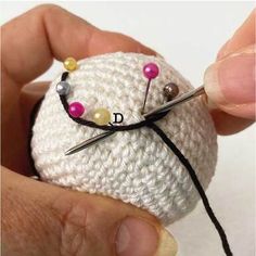 someone is knitting something with needles on top of the yarn ball that has been made into a pin cushion