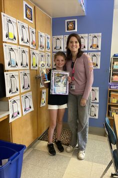 two women standing next to each other in front of a bulletin board