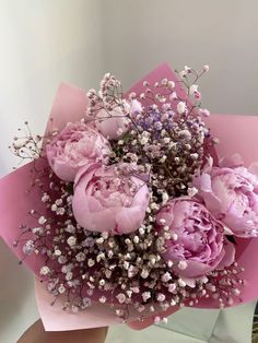 a bouquet of pink flowers is held in someone's hand, with baby's breath