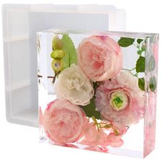 pink flowers are in a glass block on a white background