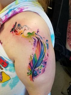 a woman with a colorful feather tattoo on her back shoulder and right arm, in front of the camera