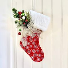 a christmas stocking hanging on a door with a white towel and holly berry decoration