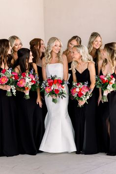 a group of women standing next to each other wearing black dresses and holding bouquets