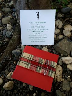 a red envelope with a note attached to it sitting on some rocks next to a tree