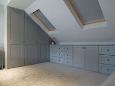 an attic bedroom with white carpet and gray cabinets