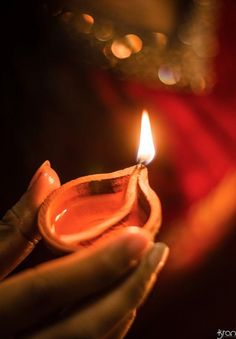 a person holding a small candle in their hand with the light on it's side