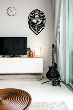 a living room with an entertainment center, guitar and clock on the wall above it