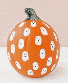 a painted pumpkin with ghost faces on it