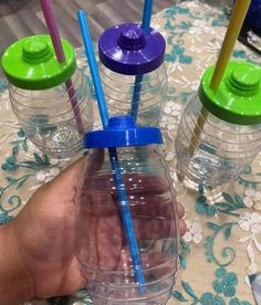 three plastic water bottles with straws in them