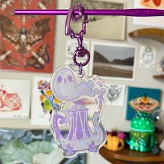 a purple keychain hanging from a wall with pictures on the walls behind it