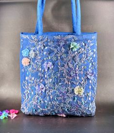 a blue handbag sitting on top of a table next to some flowers and butterflies