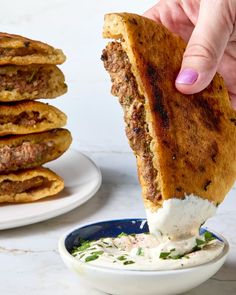 a person is dipping something into a bowl with some pita bread on the side