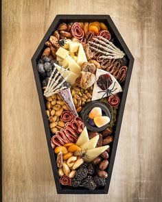 an assortment of cheeses, nuts and meats in a black tray on a wooden table