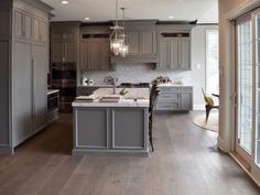 a large kitchen with gray cabinets and wood floors