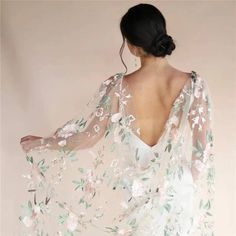 a woman in a white dress with flowers on it's shawl, back view