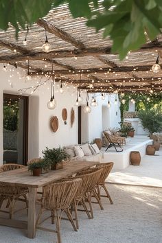 an outdoor dining area with wicker furniture and string lights hanging from the pergolated roof