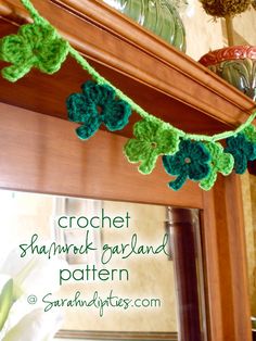 a crochet shamrock garland hanging from a mantle