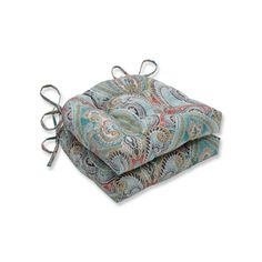 two square cushions with ties tied to each other on top of them, one in blue and the other in multicolored paisley