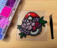 a crafting kit with beads and scissors on a table next to it is a plastic container filled with pink, purple, and green sprinkles