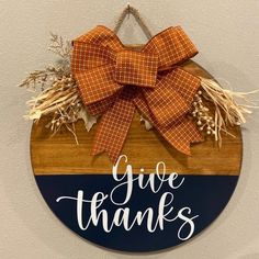 a wooden sign that says give thanks with a bow hanging on the front of it