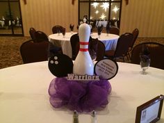 a bowling pin centerpiece sitting on top of a white tablecloth covered round table