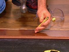 a person is holding a pencil and writing on a piece of wood that has been stained yellow