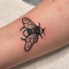 a small black and white bee tattoo on the arm