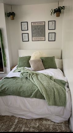 there is a bed with green blankets and pillows on top of it in the room