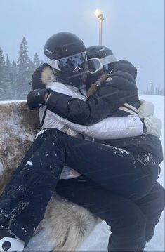 two people hugging each other while sitting in the snow