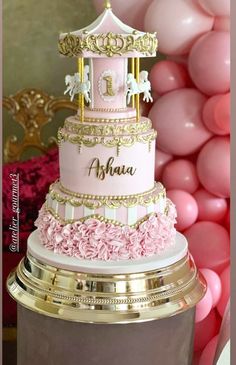 a three tiered cake with pink and gold decorations on top is surrounded by balloons