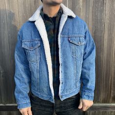 "This denim jacket is warmly lined in the most classic Levi style. Very well made by Levi in the USA, the jacket is in great condition. Beautiful metal buttons complete this men's size large button up. White synthetic shearling has been kept very clean. Jacket is men's sizing but is a unisex design. -Model size women's medium/large. -Model size men's large. Approximate measurement when laid flat: 25\" armpit to armpit 22\" shoulder to shoulder 23\" sleeve 25\" back of collar to hem" Winter Outdoor Dark Wash Denim Jacket, Medium Wash Denim Jacket For Winter Outdoor, Winter Outdoor Medium Wash Outerwear, Classic Winter Denim Jacket For Outdoor, Winter Denim Blue Outerwear With Button Closure, Denim Blue Winter Outerwear With Button Closure, Winter Denim Blue Outerwear With Snap Buttons, Denim Blue Outerwear With Snap Buttons For Winter, Vintage Winter Outerwear In Medium Wash