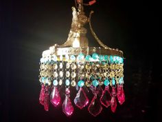 a chandelier hanging from the ceiling with lots of colorful beads and jewels on it