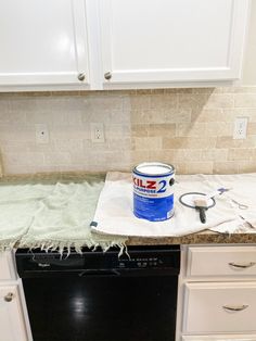 a bucket of paint sitting on top of a counter next to a dishwasher