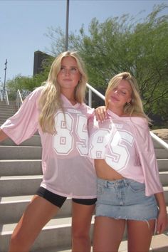 two beautiful young women standing next to each other in front of some stairs and steps