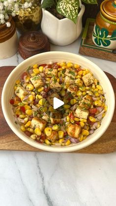 a white bowl filled with corn on top of a wooden cutting board