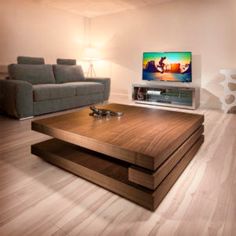 a living room with a couch, coffee table and flat screen tv on the wall