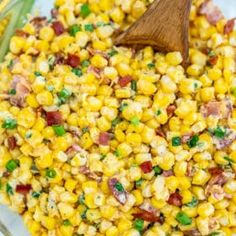 corn salad in a glass bowl with a wooden spoon