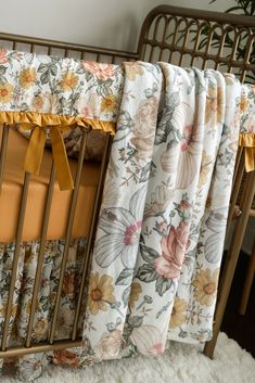 a baby crib with floral bedding and yellow bow tie hanging from it's side